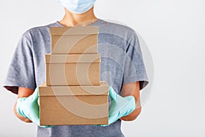 A delivery service employee holds a box with gloves and a mask to Protect it from viruses and diseases on a white background