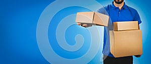 delivery service man holding cardboard boxes on blue background