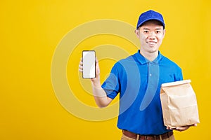 Delivery service man smiling wearing blue uniform hold paper containers for takeaway bag grocery food packet and show smartphone