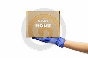 Delivery service during quarantine. Young woman hand in rubber gloves holds cardboard box with sign