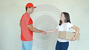 Delivery service worker in uniform delivering parcels to woman. Man holding boxes, smiling and handshake