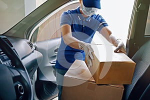 Delivery services courier during the Coronavirus COVID-19 pandemic, courier wearing medical mask and latex gloves for safety