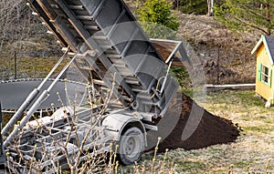 Delivery truck pouring top grade black garden soil from box to home garden.
