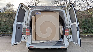 A delivery van filled with large flat cardboard boxes ready to be unloaded