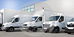 Delivery white vans in service van trucks and cars in front of the entrance of a warehouse distribution logistic