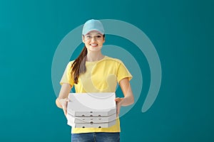 Delivery woman with cardboard pizza boxes on color background