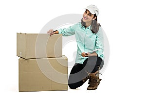 Delivery woman with clipboard kneeling by box