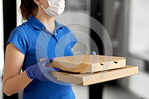 Delivery woman in face mask with pizza boxes