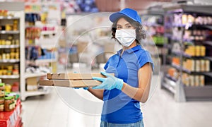 Delivery woman in mask with pizza boxes at store