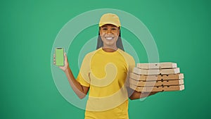 Delivery woman in uniform holding pizza boxes and smartphone, smiling at camera. Advertising area, workspace mockup.