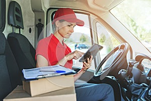 Delivery woman using digital tablet while sitting in van