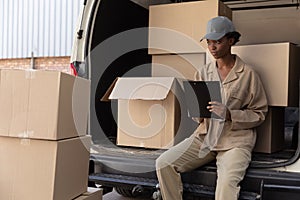 Delivery woman writing on clipboard near van outside the warehouse