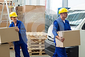 Delivery workers unloading cardboard boxes from pallet jack