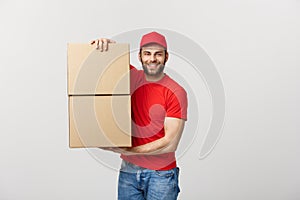 Delivery young man in red uniform holding two empty cardboard boxes isolated on white background. Copy space for