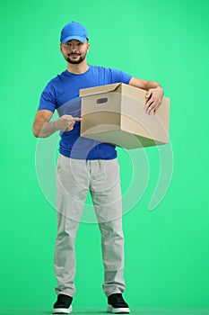 The deliveryman, in full height, on a green background, points to the box