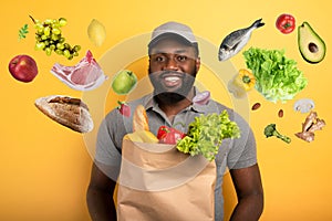 Deliveryman with happy expression ready to deliver bag with food. Yellow background.