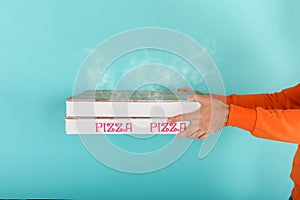 Deliveryman holds bizza boxes ready to be delivered . cyan background