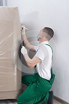 Deliveryman in a protective mask and white gloves, rewrites the batch and delivery number before paperwork