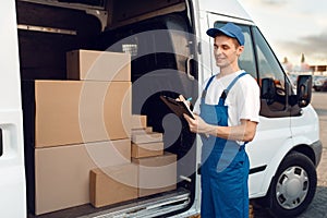 Deliveryman in uniform, carton boxes in the car photo