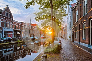 Delt canal with old houses and cars parked along on sunset