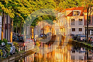 Delt canal with old houses and cars parked along on sunset