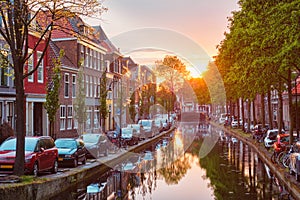 Delt canal with old houses and cars parked along on sunset