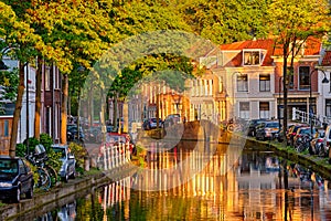 Delt canal with old houses and cars parked along on sunset