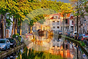 Delt canal with old houses and cars parked along on sunset