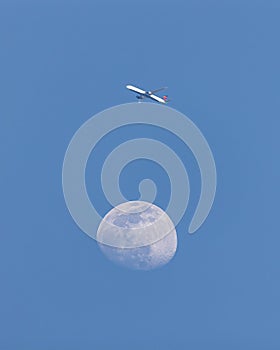 Delta airlines plane flying across the sky near an almost full moon.