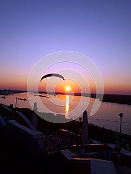 Delta glider flying over the river Volga at sunset