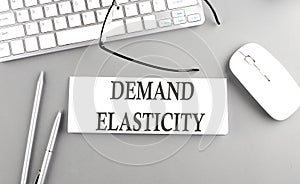 DEMAND ELASTICITY text on paper with keyboard on grey background photo