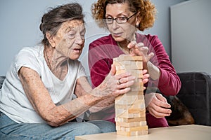 Dementia therapy. Social worker and dog plays an educational board game with senor patient at nursing home. Jenga game. Caregiver