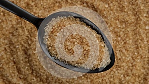 Demerara golden brown sugar in black spoon