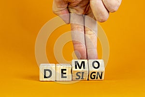 Demo and design symbol. Businessman hand turns cubes and changes the word `design` to `demo`. Beautiful orange background.