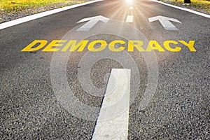 Democracy written on road with white arrow on asphalt road