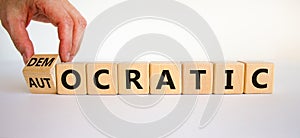 Democratic or autocratic symbol. Male hand turns a cube and changes the word `autocratic` to `democratic`. Beautiful white