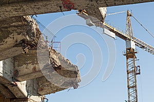 Demolished bridge on the background of a construction crane. Destroyed building. Demolition of the structure.
