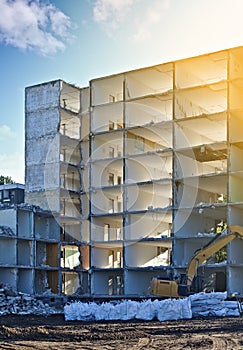 Demolished residential building with excavator and plastic bags filled with rubble in the foreground