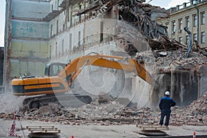Demolition of building. Excavator breaks old house. Freeing up space for construction of new building photo