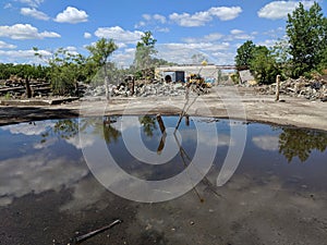 Demolition bulldozer water rubble trees sky