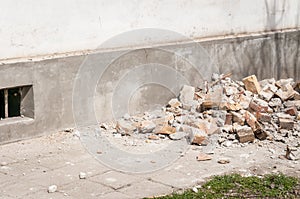 Demolition and destruction site bricks remains of building material on the ground by the house foundation base