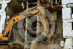 Demolition of a five-story apartment building recognized as emergency housing, close-up of an excavator bucket collects