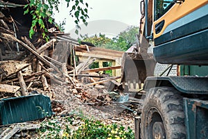 Demolition of house. Broken walls of old building and excavator at site of future construction