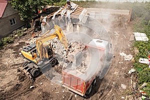 Demolition Of House Building For New Construction. Excavator Bucket Load Garbage into Truck, Aerial View