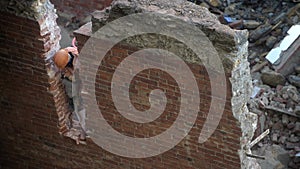 Demolition of old abandoned house, workman in orange helmet destroy wall with jackhammer. Deconstruction of living house