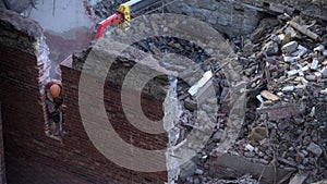 Demolition of old abandoned house, workman in orange helmet destroy wall with jackhammer. Deconstruction of living house