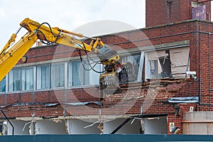 Demolition of an old building with a long reach machine hydraulic jaw.