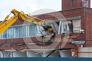 Demolition of an old building with a long reach machine hydraulic jaw.