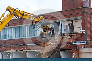 Demolition of an old building with a long reach machine hydraulic jaw.