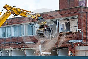 Demolition of an old building with a long reach machine hydraulic jaw.